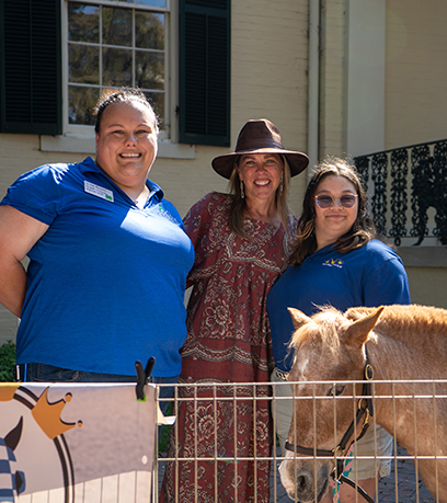 La Première dame pose avec deux dresseurs de chevaux portant et un cheval miniature nommé cinnamon.