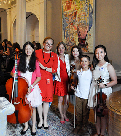 La Première dame et la secrétaire d'État à l'éducation, Aimee Guidera, sont aux côtés d'un groupe d'élèves scolarisés à domicile qui tiennent des instruments de musique.