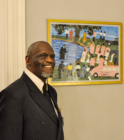 Un artiste se tient à côté de sa peinture colorée.