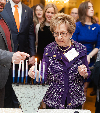 Halina Zimm, survivante de l'Holocauste, utilise une bougie pour allumer une menorah.
