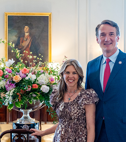Le gouverneur et la première dame posent devant la composition florale de la salle à manger lors de la Journée des jardins historiques.