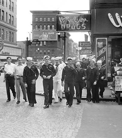 Photographie en noir et blanc de marins de la marine des années 1940 marchant dans une rue de Norfolk, en Virginie.