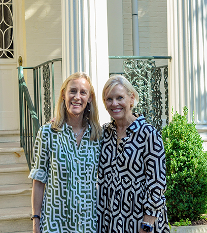 Deux femmes, vêtues de robes géométriques, se tiennent devant l'Executive Mansion.