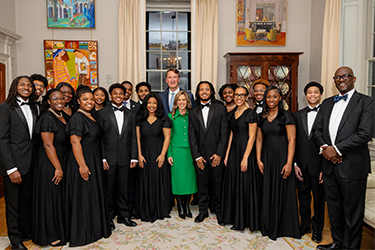 Un groupe habillé en tenue de soirée pose pour une photo avec une femme en tailleur vert.